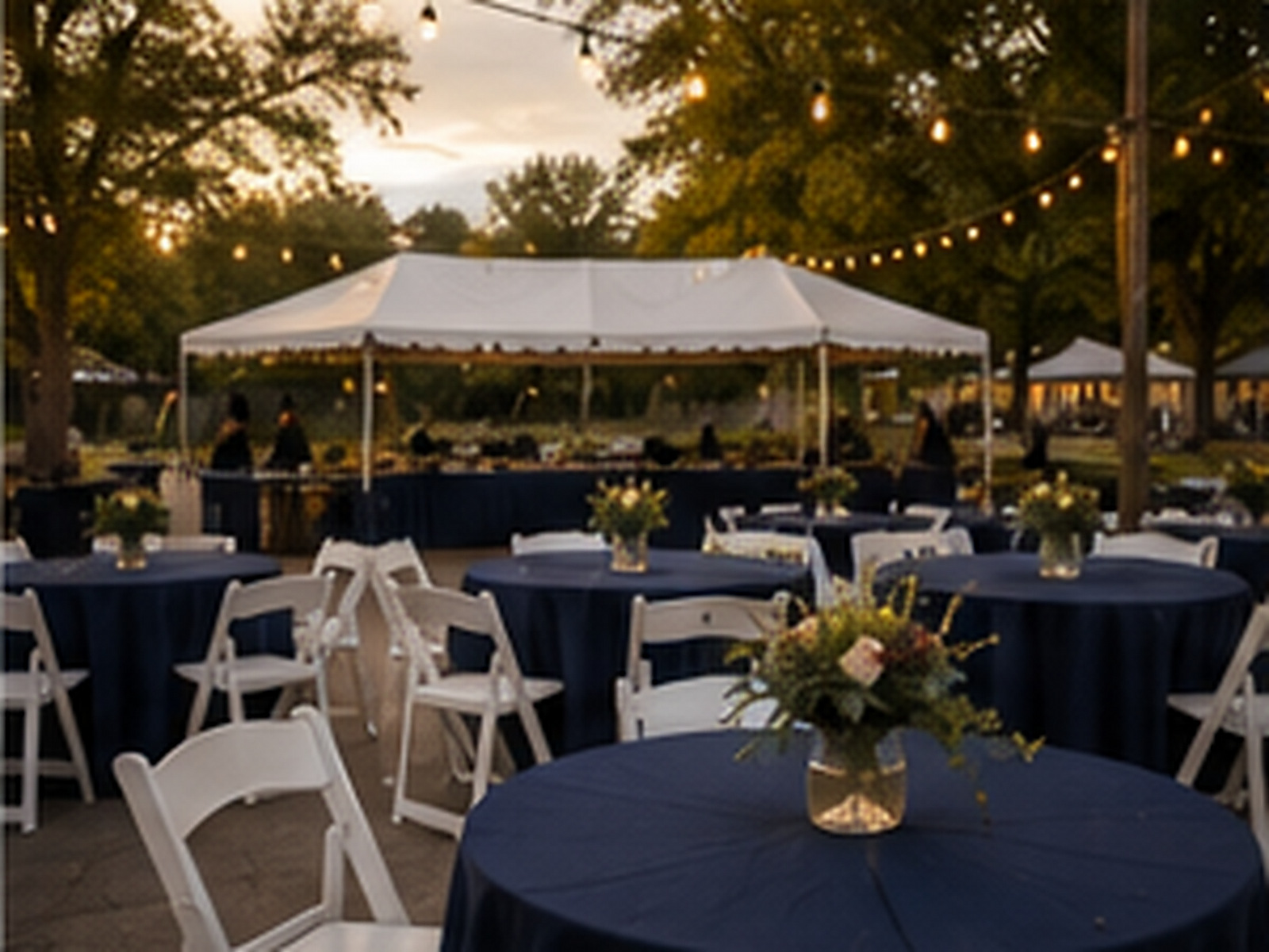 Invitados bajo una carpa en un evento al aire libre al atardecer.
